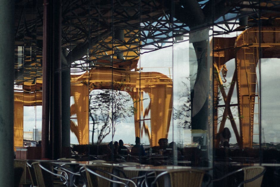 Reflective glass showing modern architecture in Nazaré, Brazil with vibrant yellow structures.