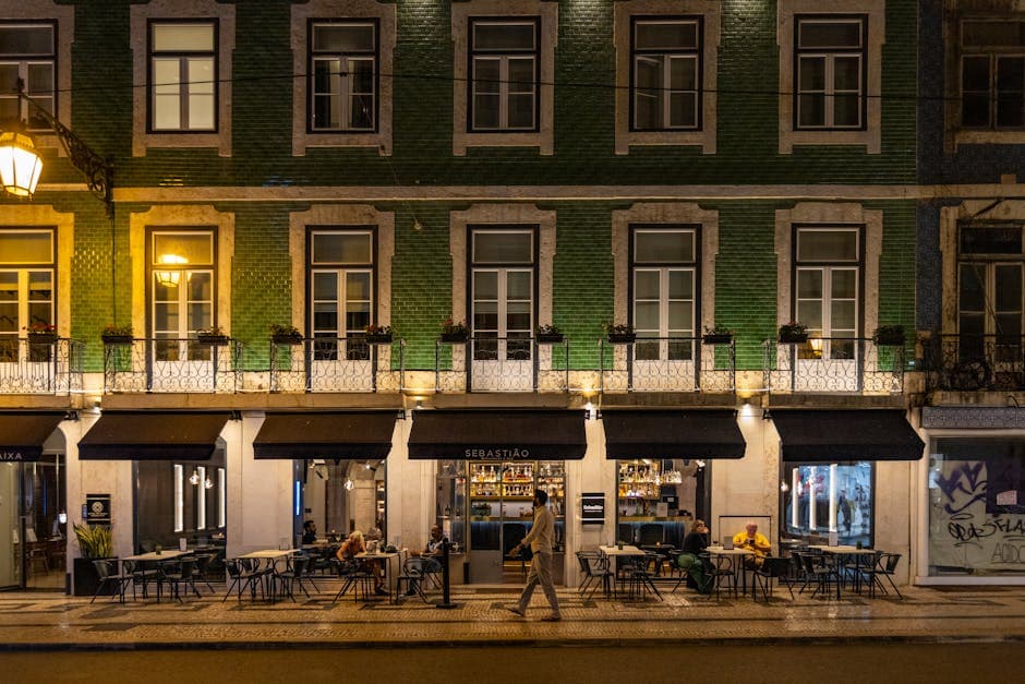 Cozy Lisbon café at night with patrons enjoying outdoor seating on a lively street.