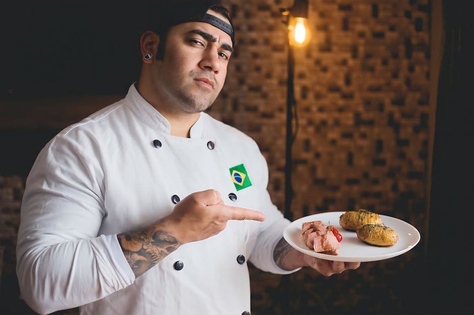 Chef in white uniform pointing at gourmet meal on plate, showcasing culinary skills.