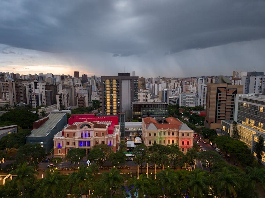 A dramatic skyline of Belo Horizonte captured with colorful historic buildings and looming storm clouds.