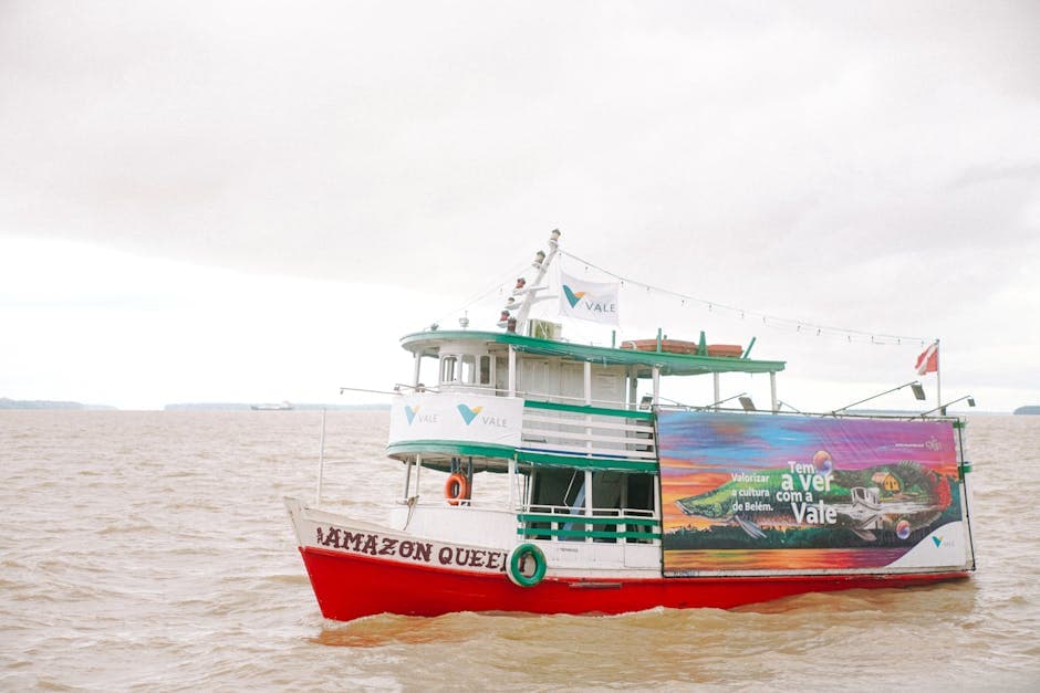 A colorful boat named Amazon Queen cruising on the Amazon River under a cloudy sky.