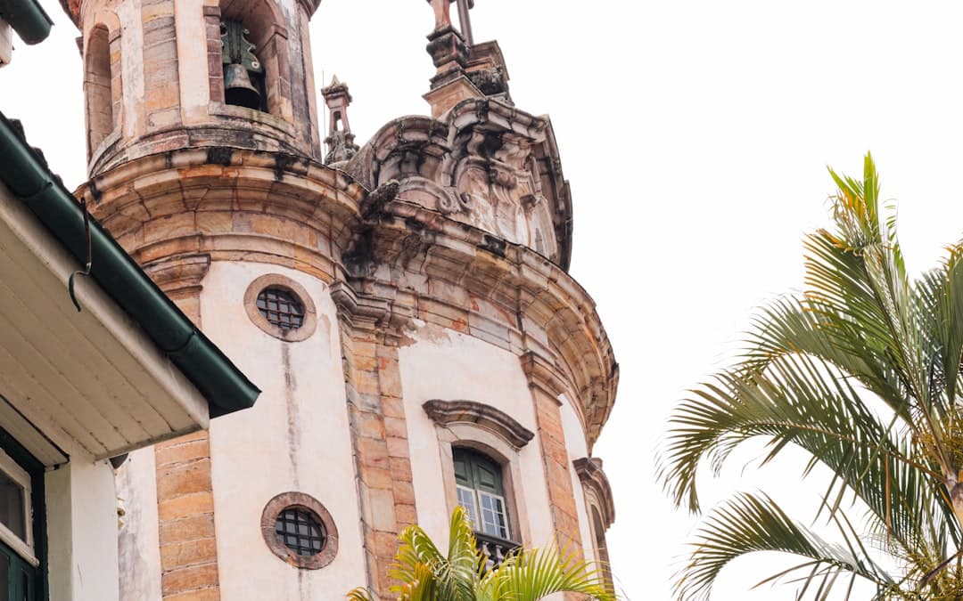 Ornate church tower with bell and palm fronds.