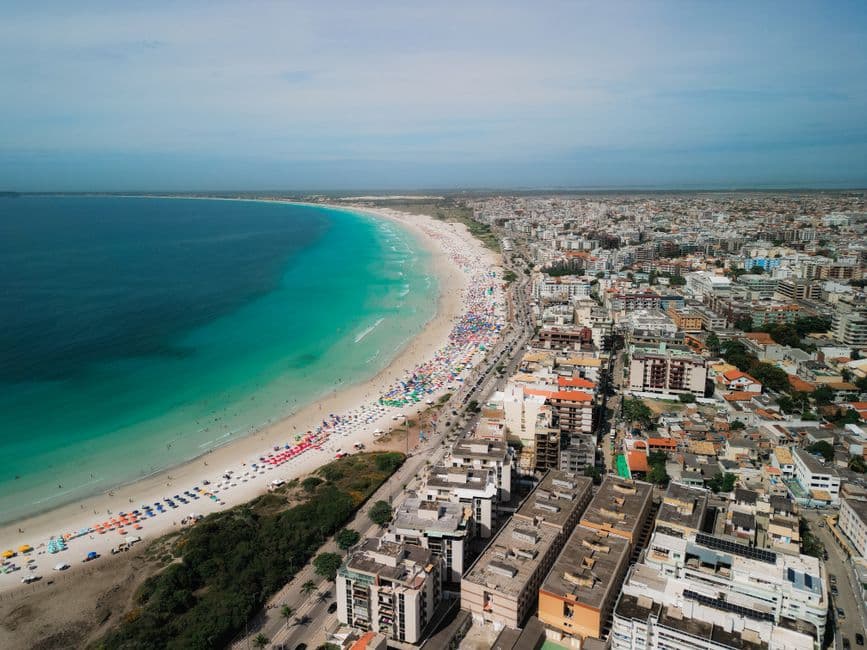 A stunning aerial view of a vibrant beach with cityscape by the turquoise sea.