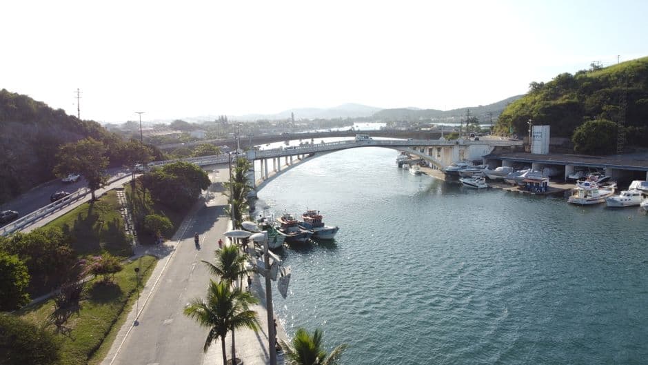 Aerial view of a picturesque bridge and waterway in Cabo Frio, Brazil with boats and lush greenery.