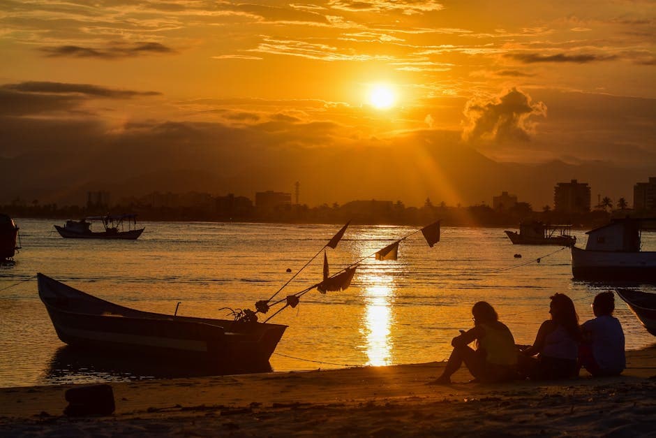 Enjoy a serene sunset on Caraguatatuba beach, Brazil with silhouettes and boats.