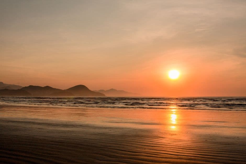 A serene sunset scene at Caraguatatuba beach, featuring a vibrant horizon and tranquil waves.