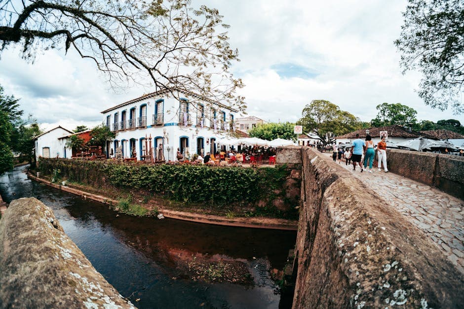 Lively street scene captured in Tiradentes, Brazil, featuring a historic bridge and bustling atmosphere.