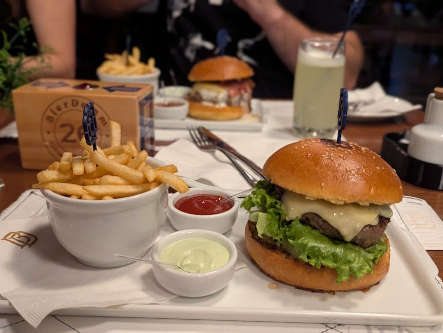 A delectable cheeseburger served with fries and dips on a restaurant table setting.