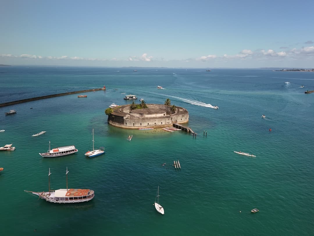 Fortress island surrounded by boats in clear blue water.