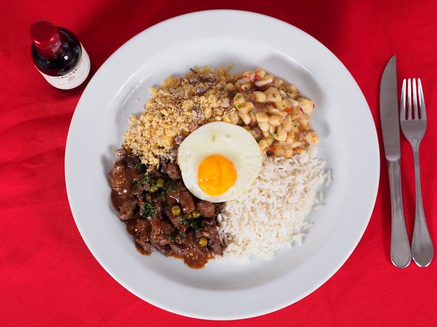 A vibrant Brazilian Feijoada meal with rice, beans, and a fried egg on a red background.