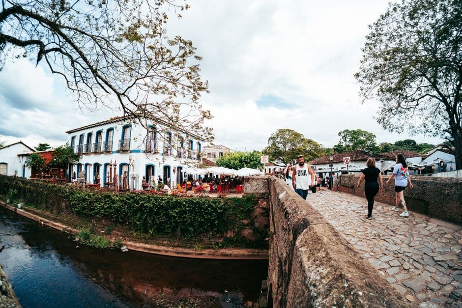A picturesque street scene in Tiradentes, Brazil with people strolling by a historic building.