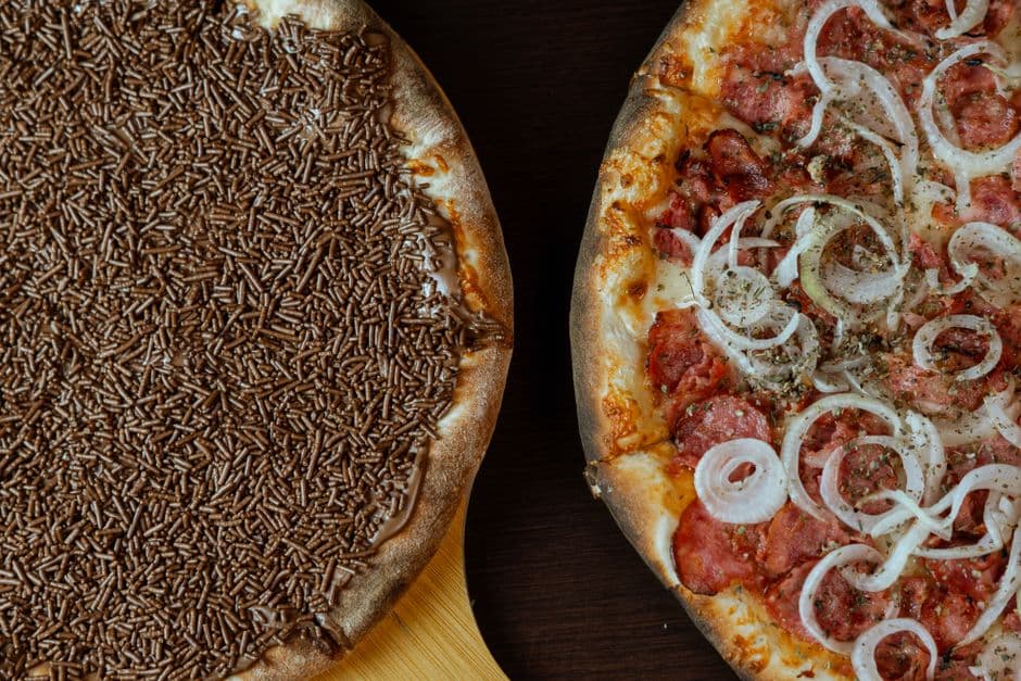 Close-up of chocolate and savory pizza halves on a wooden surface.