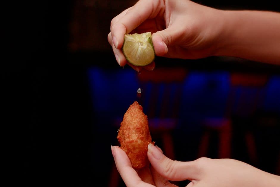 Close-up of lime being squeezed over a fried snack in Recife, Brazil.