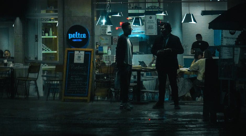 Moody and atmospheric street view of a bustling nighttime restaurant scene.