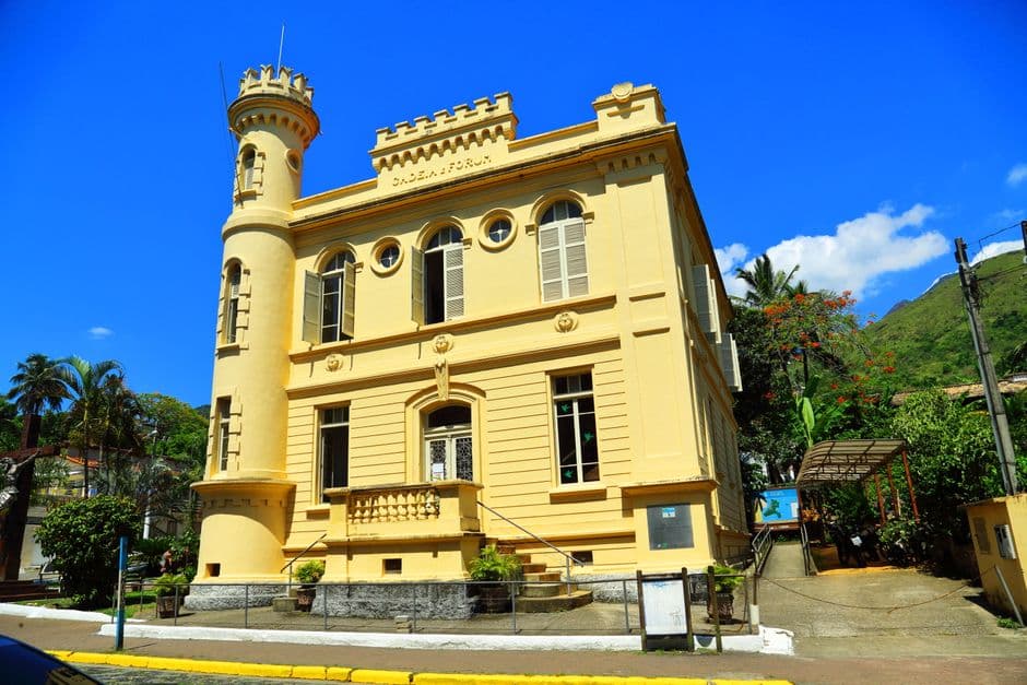 Charming historic building with a yellow facade and turret against a clear blue sky.