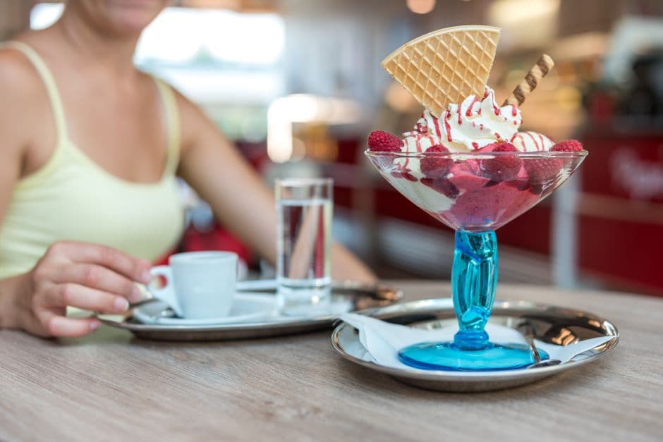 Appetizing berry ice cream sundae with waffle cone, served with coffee in a modern cafe.