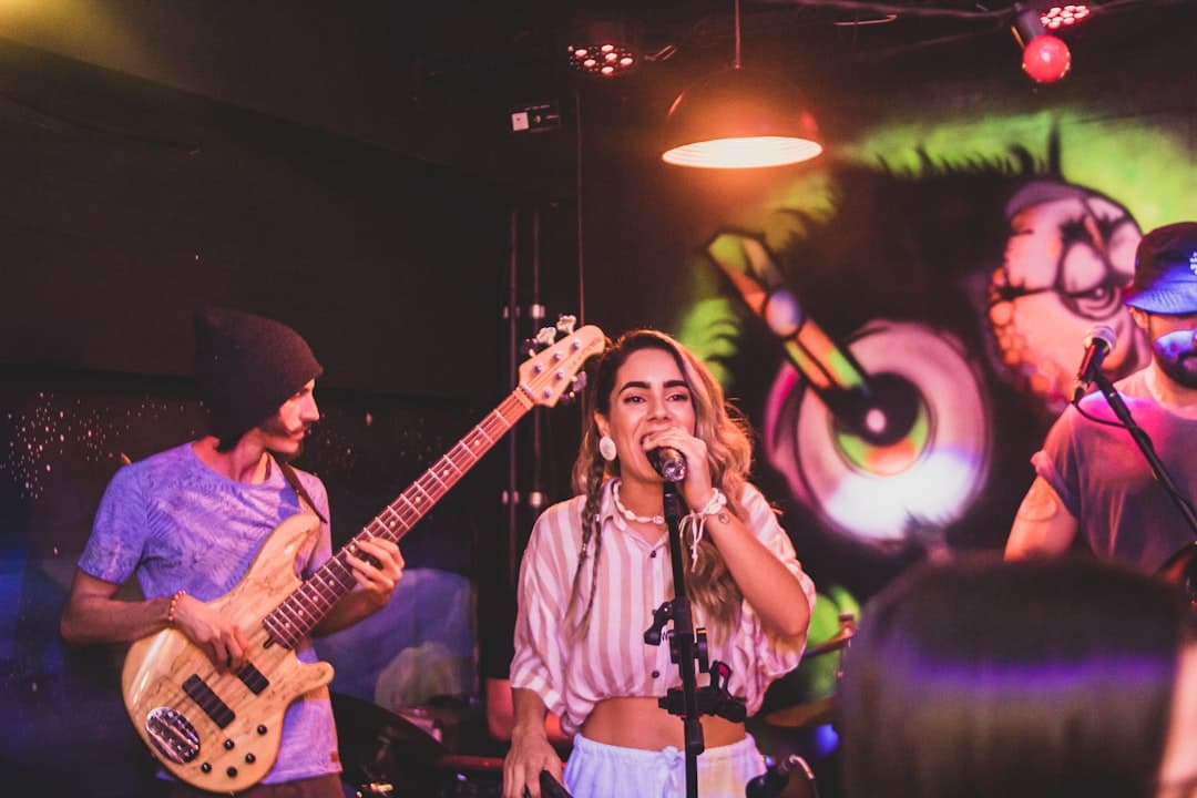a woman singing into a microphone while holding a guitar