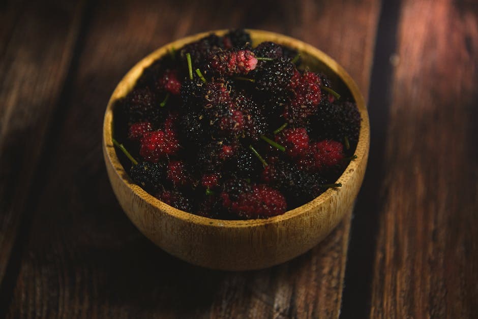 Close-up of juicy blackberries in a wooden bowl on a rustic surface. Perfect for healthy eating themes.