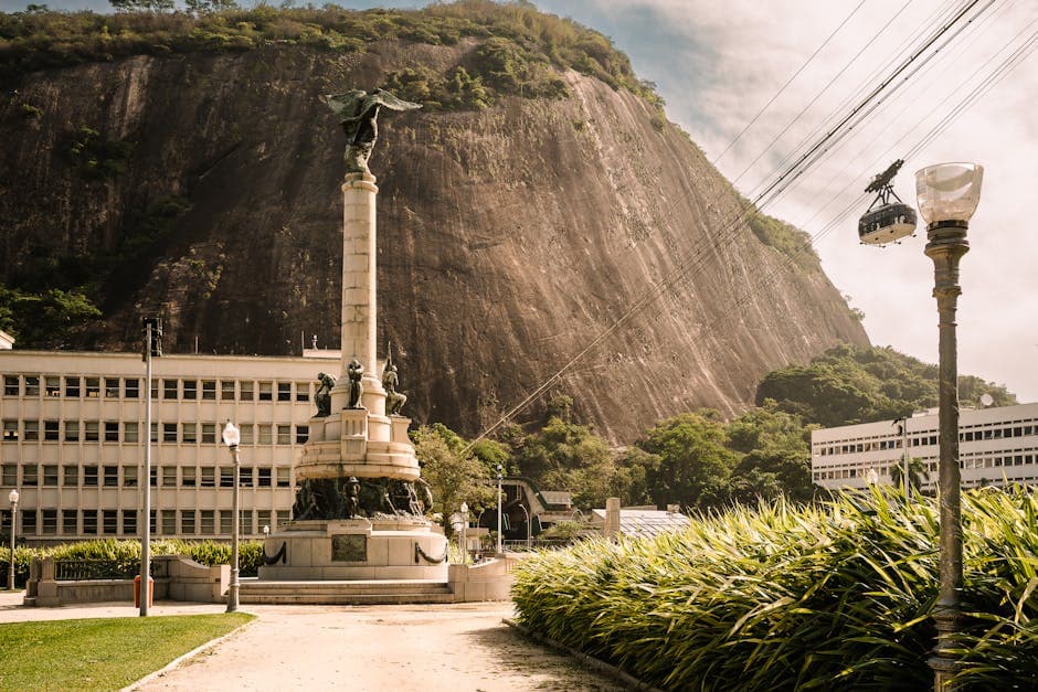 A statue with cable cars and mountain backdrop in Rio de Janeiro, Brazil.