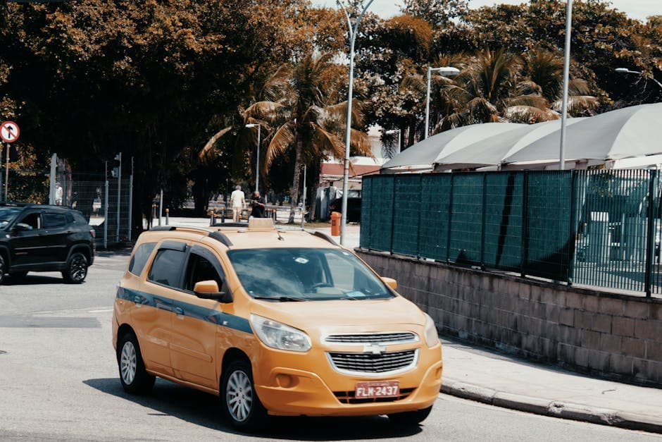 A yellow taxi drives through the bustling streets of Rio de Janeiro, Brazil, under sunny skies.