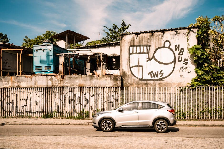 A car passes graffiti-covered buildings in sunny Rio de Janeiro, Brazil.