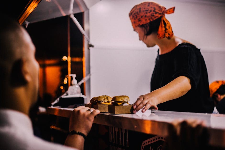 A street vendor in Maceio, Brazil serves burgers at a night market food stall.