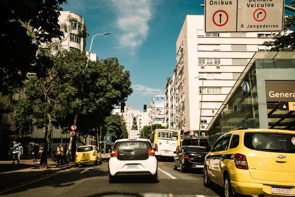 Capture of a lively street in Rio de Janeiro, featuring traffic and pedestrians on a sunny day.