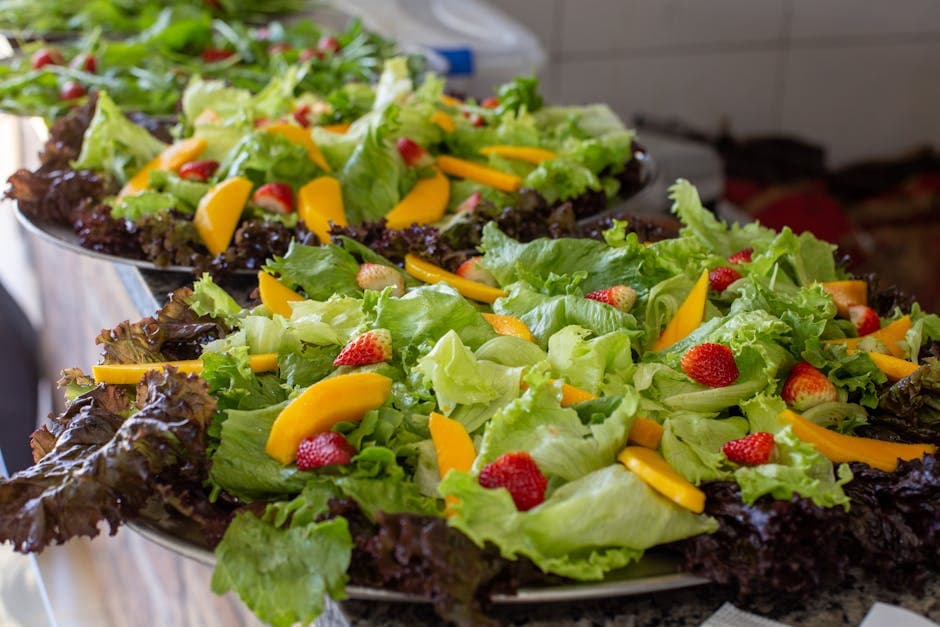 Close-up of fresh mixed fruit and lettuce salad platter with vibrant strawberries and mango slices.