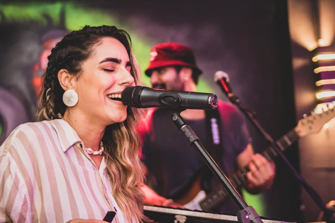 a woman singing into a microphone while holding a guitar