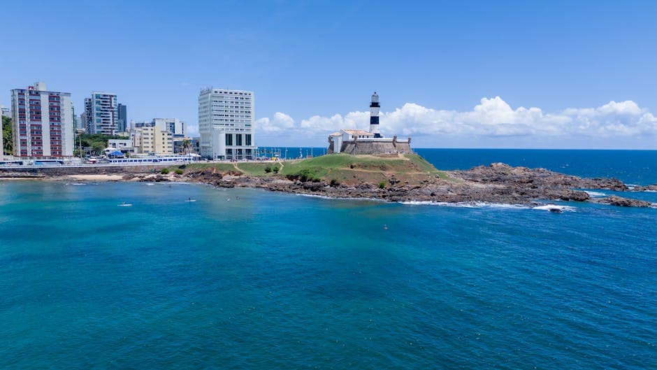 Scenic aerial view of Barra Lighthouse and coastal skyline in Salvador, Brazil, with clear blue sea.