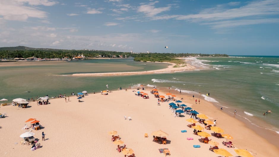 Aerial view of vibrant beach in Lauro de Freitas, Bahia, with colorful umbrellas and sunbathers.