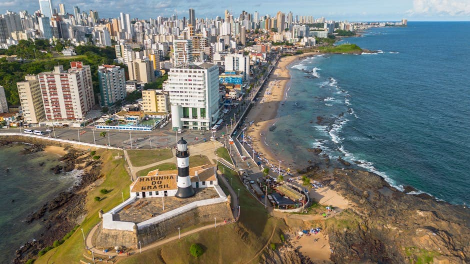 Stunning aerial photo of Barra Lighthouse with Salvador cityscape and coastline in Brazil.