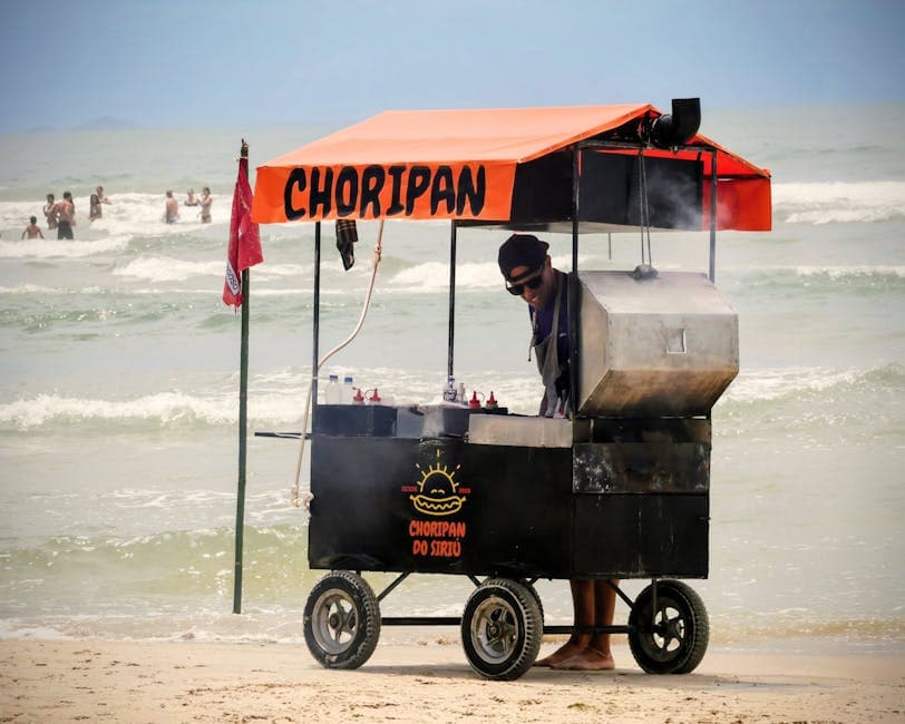 Vendor cooking at a Choripan cart on a lively beach scene.