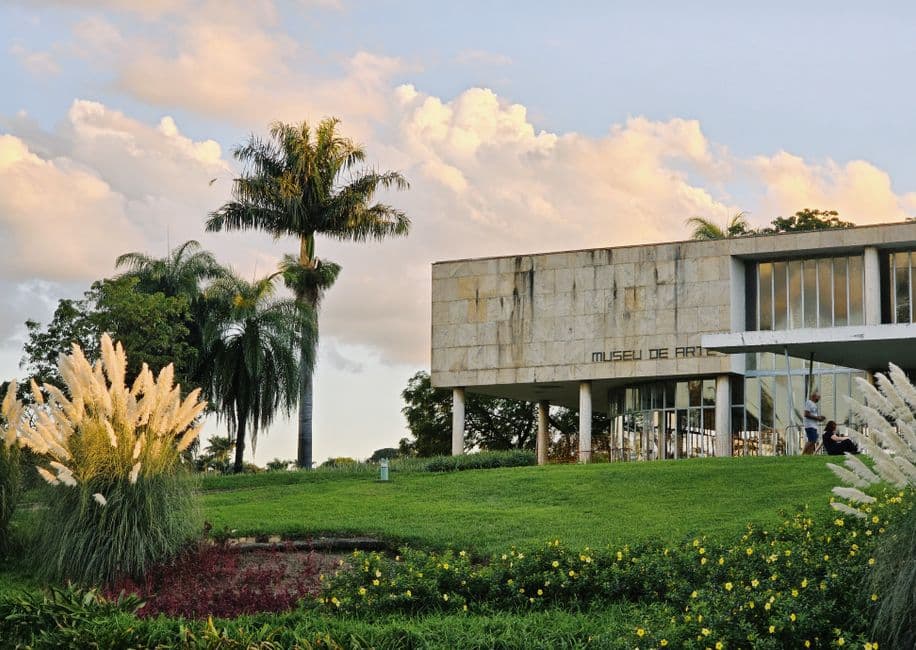 Scenic view of Pampulha Art Museum in Belo Horizonte, surrounded by lush greenery under a vibrant sky.
