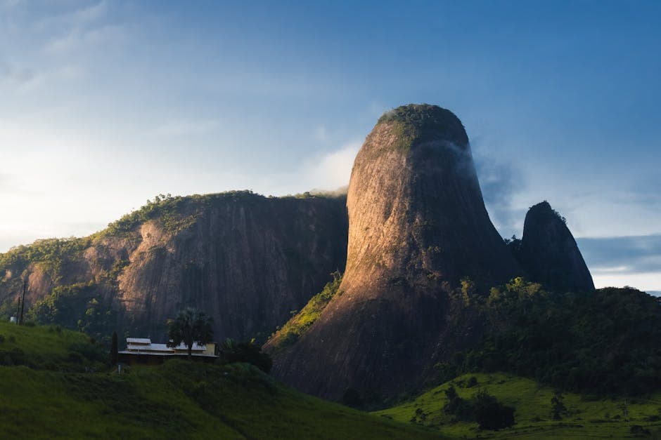 A stunning view of a unique mountain formation bathed in soft morning light, surrounded by lush green landscape.