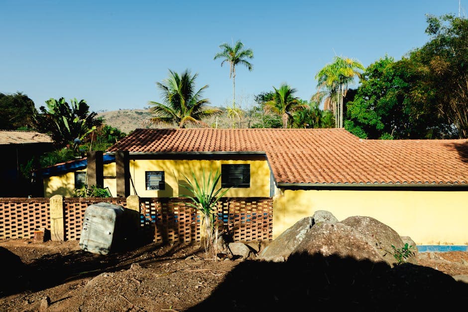 Yellow farmhouse amidst tropical plants, rural setting in Espírito Santo do Pinhal, Brazil.