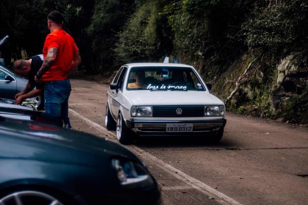 a man standing next to a white car on a road