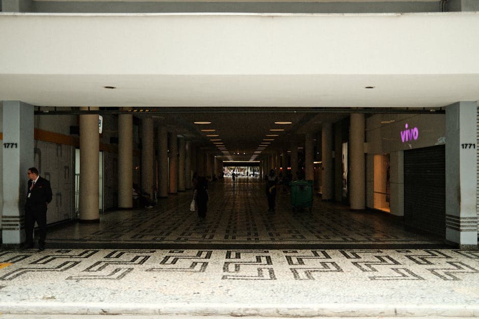 Spacious corridor in a modern shopping center with minimal lighting and people walking.