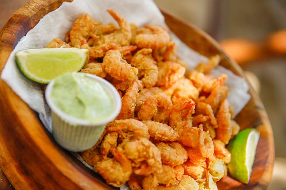 Delicious deep-fried shrimp served with fresh lime wedges and creamy sauce.
