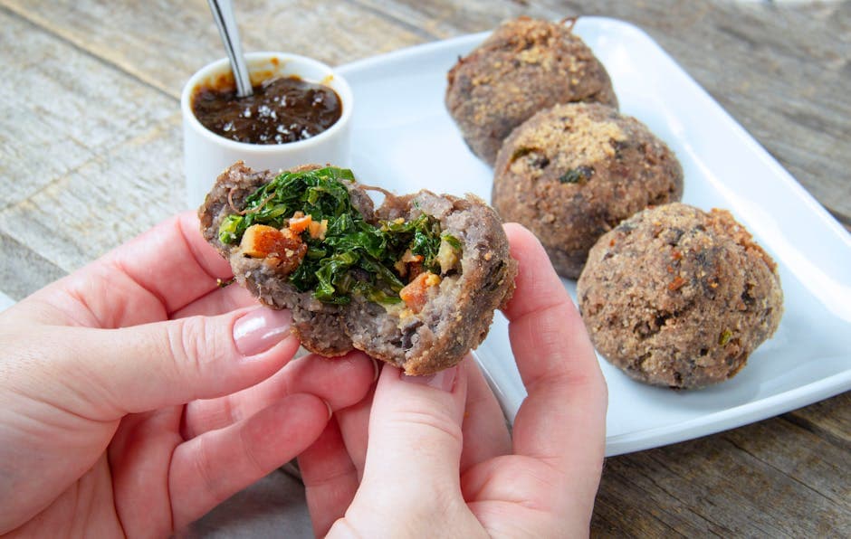 Close-up of Brazilian acarajé with a green filling, served with sauce. Delicious street food from São Paulo.