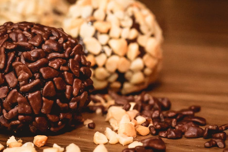 Delicious close-up of Brazilian brigadeiros with chocolate sprinkles and chopped nuts on a wooden table.