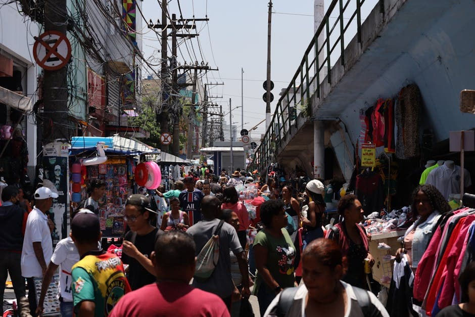 Crowded street market in São Paulo with diverse people and colorful stalls.