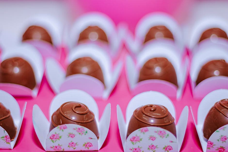 Rows of enticing chocolate truffles elegantly placed in floral wrappers for a celebration.