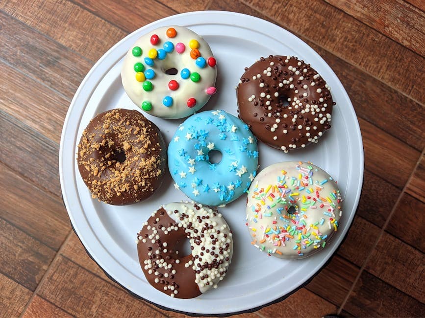 A vibrant assortment of decorated donuts placed on a white plate, perfect for any dessert lover.