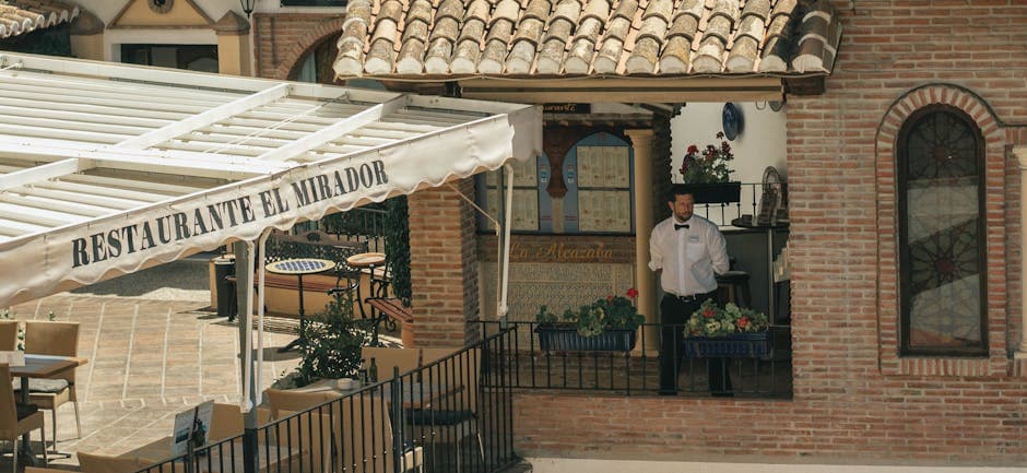 Outdoor view of a traditional Spanish restaurant with a waiter and rustic architecture.