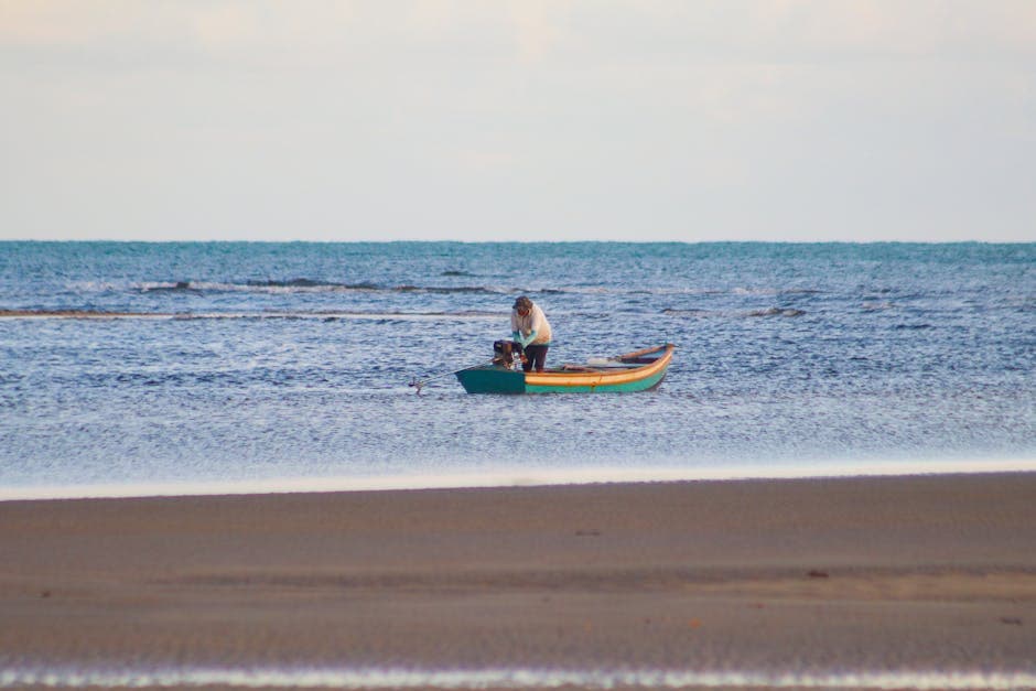 A lone fisherman in a colorful boat on the calm sea near the Brazilian coast.