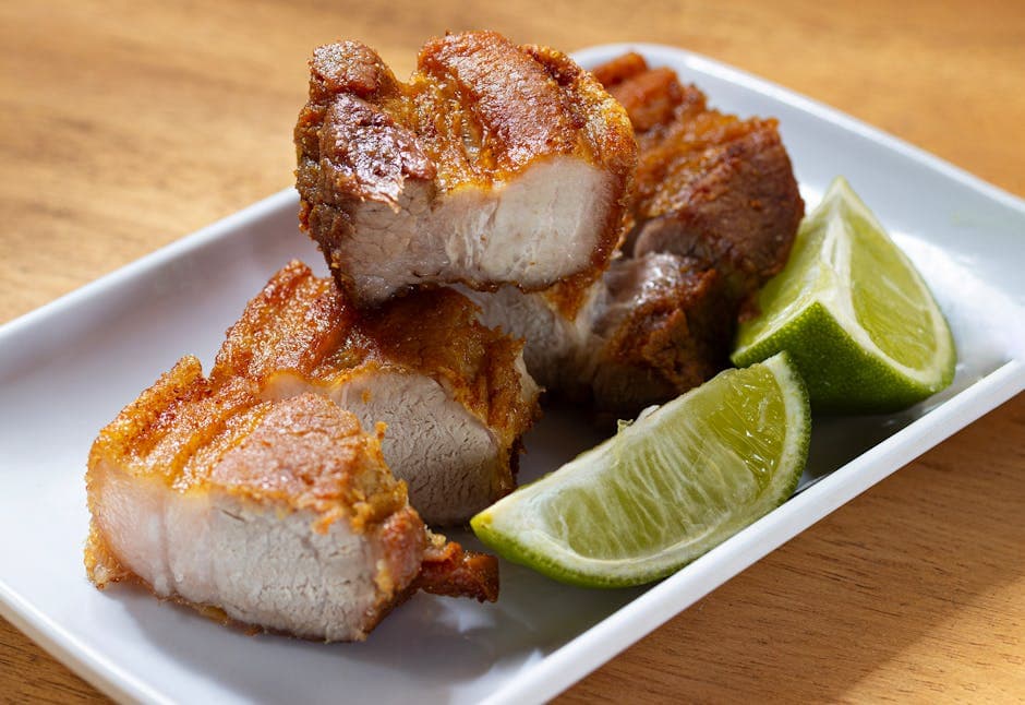 Tasty crispy pork belly served on a plate with fresh lime wedges, perfect for a flavorful meal.
