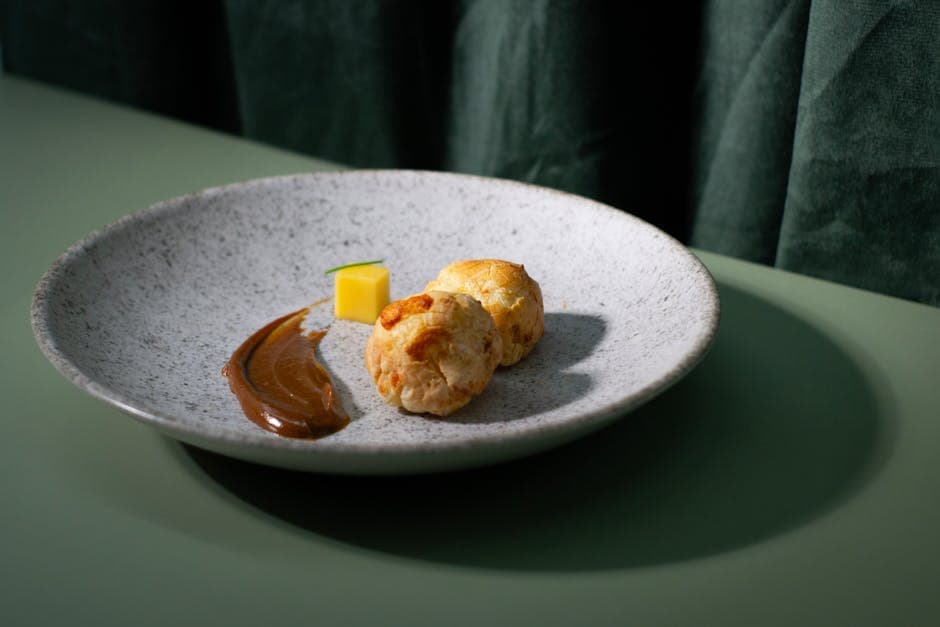Sophisticated Brazilian cheese bread plated elegantly with chocolate sauce and mango dice.