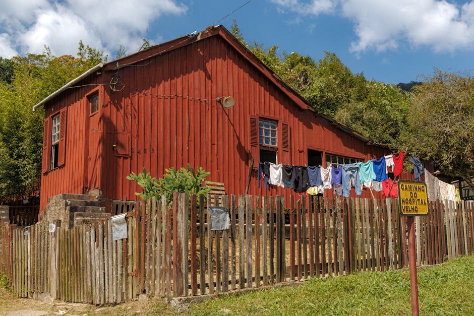 Rustic red house with laundry line on wooden fence in scenic Paranapiacaba, São Paulo, Brazil.