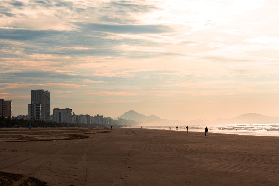 Scenic view of São Vicente beach at dusk with city skyline and mountains in Brazil.